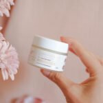 Pot ouvert de crème hydratante précieuse maman 50 g tenu dans une main